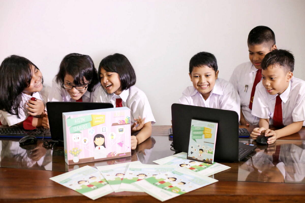 Siswa belajar bersama menggunakan laptop dan buku di kelas