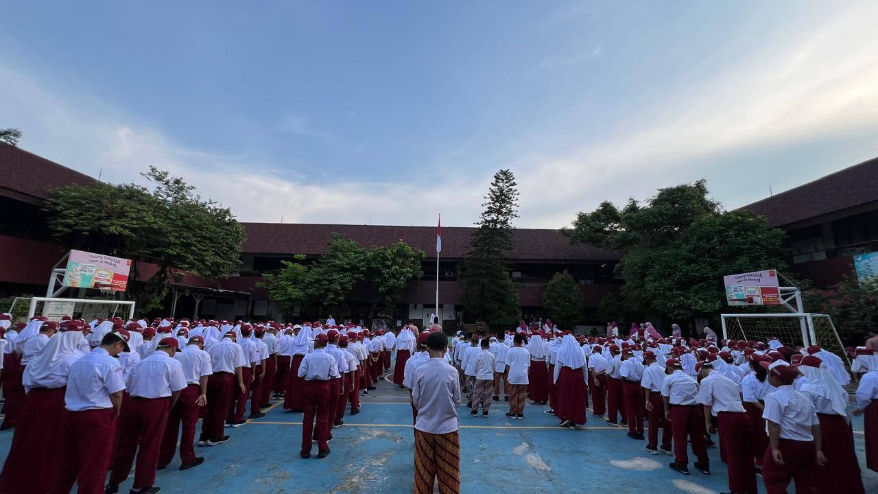 Siswa SD berseragam merah putih berbaris mengikuti upacara bendera di halaman sekolah