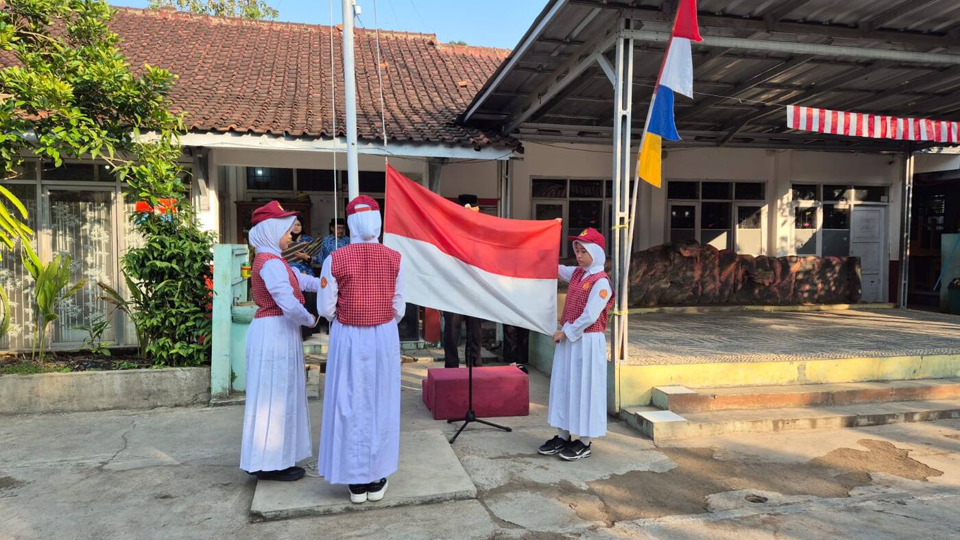 Siswi petugas upacara mengibarkan bendera merah putih di depan gedung sekolah